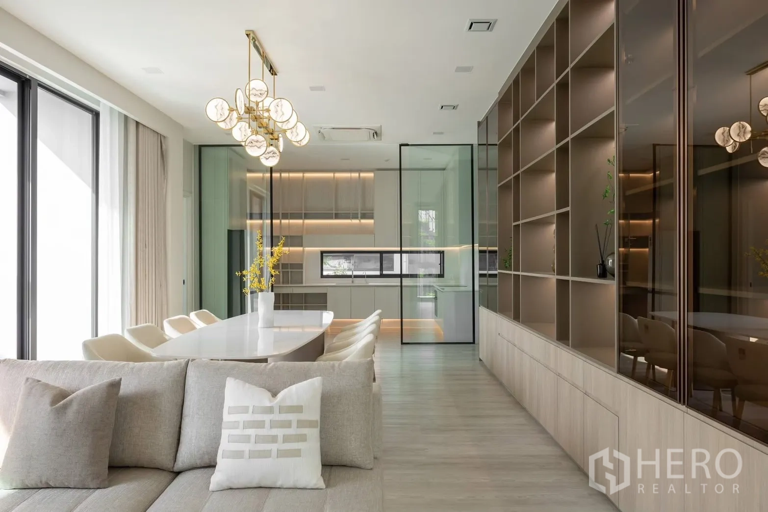 Detached House for rent in Saphan Sung, Bangkok - Bright open-plan dining and living area with glass-partitioned kitchen and full-height shelving.