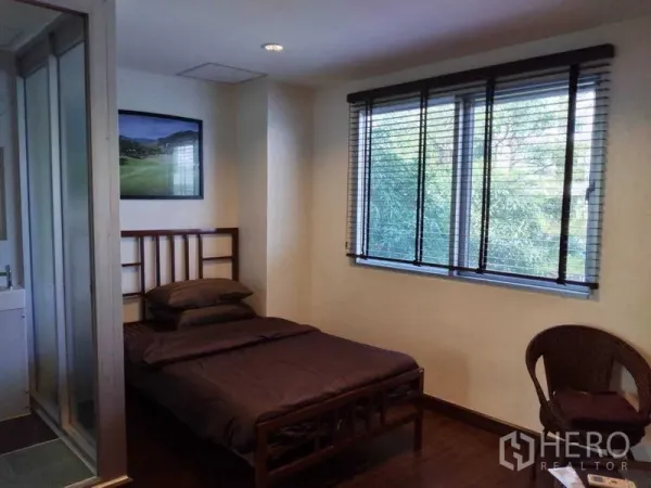 Shophouse for rent in Watthana, Bangkok - Sunny bedroom with large window and blinds, wood floors, and en-suite bathroom.