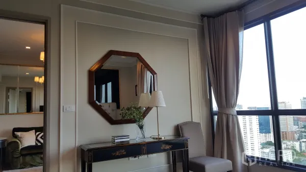 公寓 出租在Watthana, Bangkok - 优雅玄关桌与八边形镜子，旁有座椅与大窗，可观城市景色。