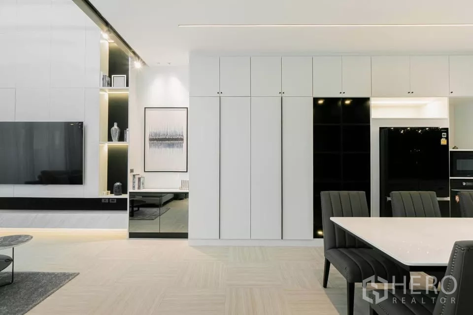Townhouse for sale in Chatuchak, Bangkok - Built-in cabinetry and illuminated shelves beside a large flat-screen TV.