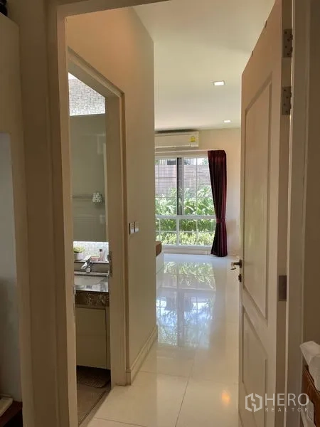 Detached House for rent in Bang Phli, Samut Prakan - Hallway leading to a bright bedroom with a large window and an adjacent bathroom.