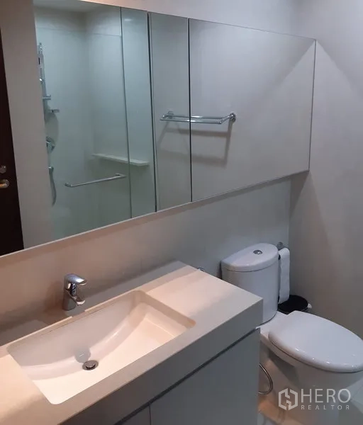 公寓 出租在Watthana, Bangkok - 现代卫浴，宽大洗手台、镜柜、坐便器与玻璃淋浴间。