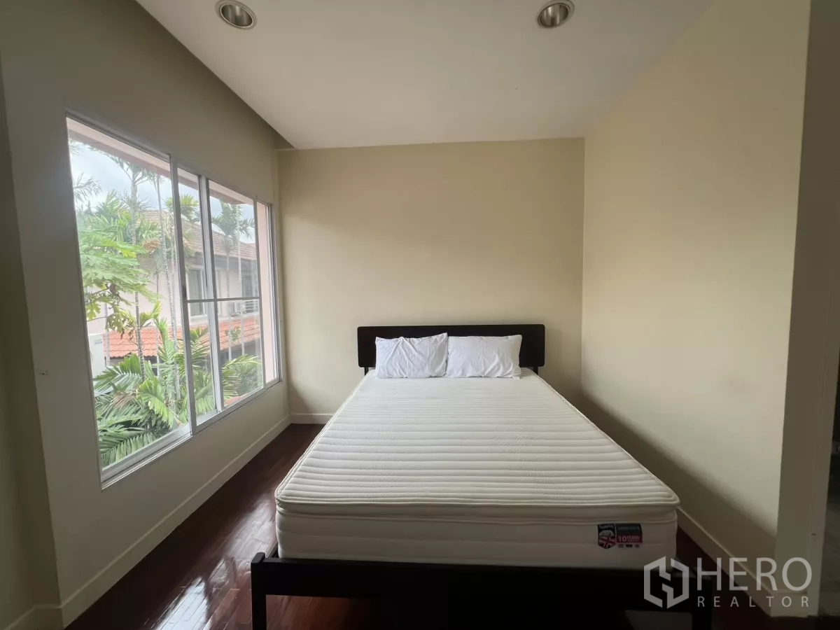 Detached House for rent in Wang Thonglang, Bangkok - Bedroom with corner windows and doorway to an ensuite bathroom.