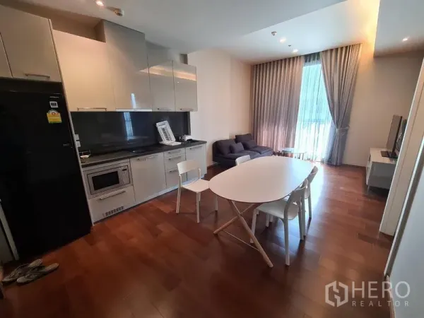 Condominium for rent in Watthana, Bangkok - Open‑plan living and kitchen in a Thonglor condo with glossy cabinets, dining table and warm wood floors.