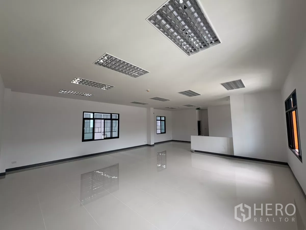 Factory for rent in Bang Pakong, Chachoengsao - Large open office space with fluorescent ceiling fixtures and glossy tiles.