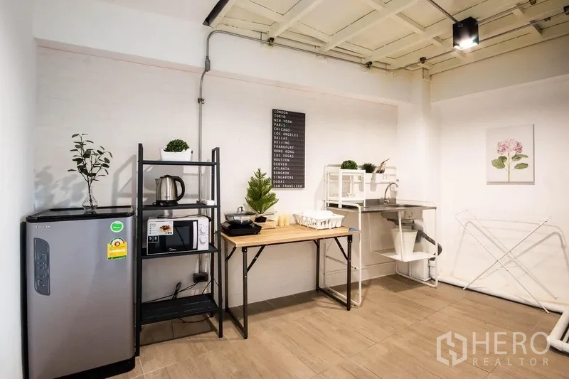 Home Office for rent in Phaya Thai, Bangkok - Pantry corner featuring fridge, counter space and storage racks on wood-look tiles.