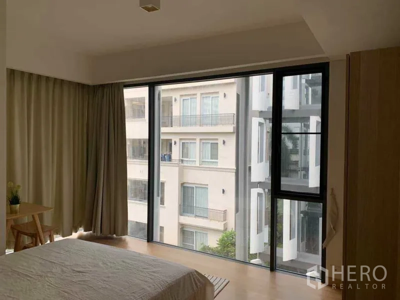 公寓 出租在Watthana, Bangkok - 卧室落地窗采光充足，可眺望邻近建筑景致。