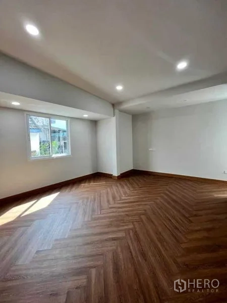 Townhouse for sale in Phra Khanong, Bangkok - Spacious living area with herringbone wood floors and recessed ceiling lights.