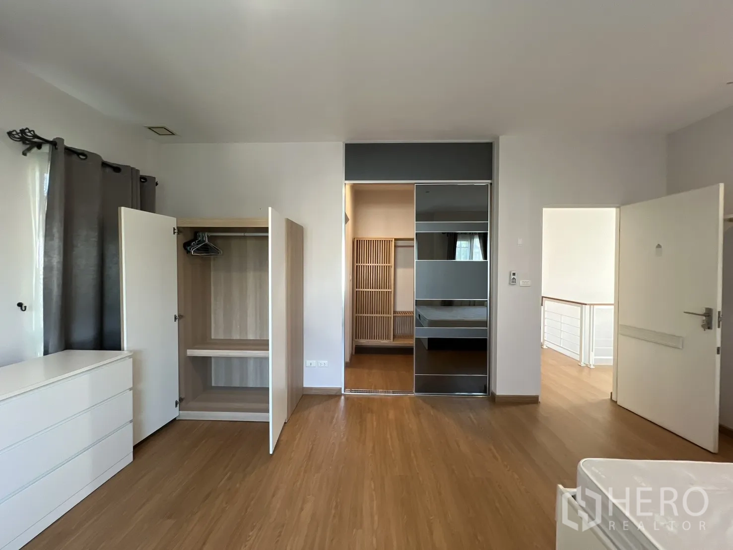 Detached House for rent in Bang Kapi, Bangkok - Spacious bedroom with open wardrobes and warm wood flooring.