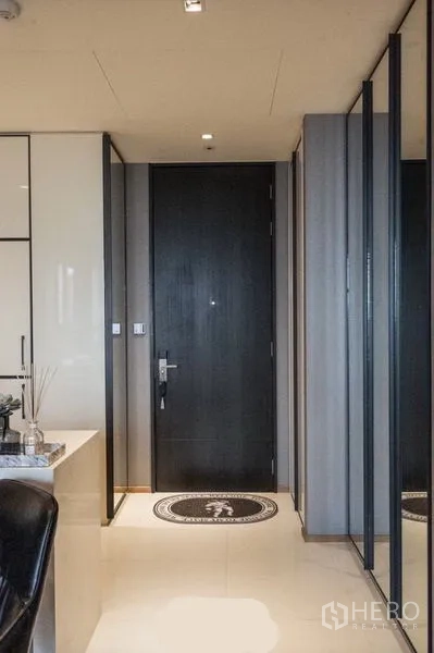 Condominium for rent in Khlong Toei, Bangkok - Entry hallway with black front door, mirrored wardrobes and light tiled flooring.