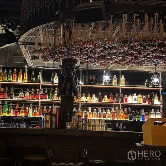 Retail Space for rent in Watthana, Bangkok - Dimly lit bar interior with illuminated liquor bottle shelves and decorative ceiling feature.