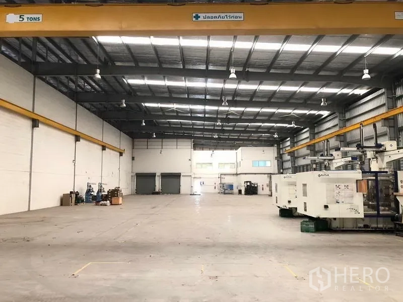 Factory for rent in Bang Sao Thong, Samut Prakan - Wide factory floor featuring 5‑ton gantry cranes and machinery along one side.