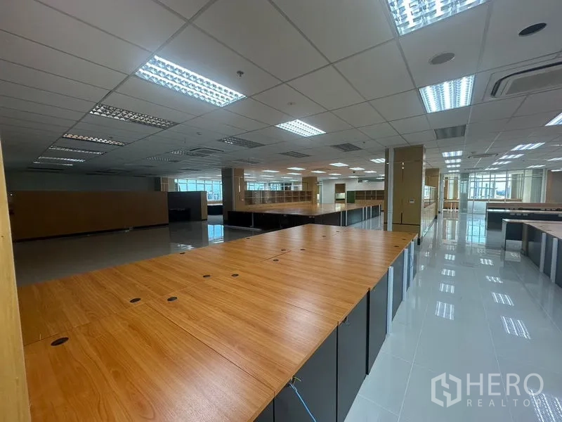 Office Space for rent in Suan Luang, Bangkok - Close-up of benching workstations with cable ports under modern grid lighting in an open-plan layout.