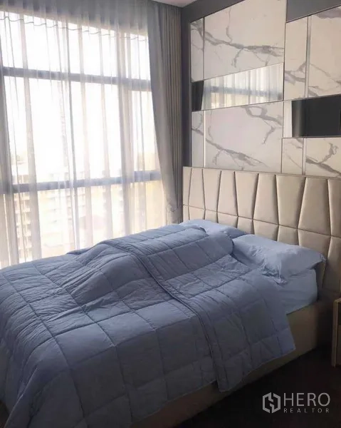 Condominium for rent or sale in Watthana, Bangkok - Second bedroom with marble accent wall, large windows and upholstered headboard.