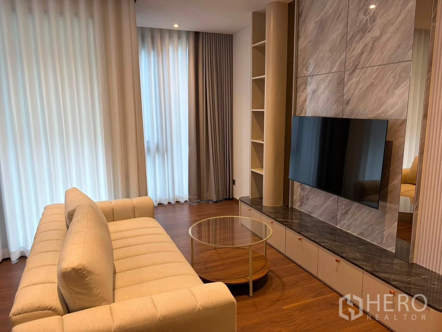 公寓 for rent in Watthana, Bangkok - 客厅配米色沙发、圆形玻璃茶几与大窗帘。