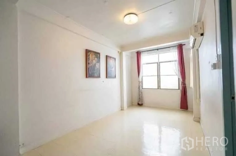 Detached House for rent in Khlong Toei, Bangkok - Sunlit empty room with glossy tile floor, wall-mounted air conditioner, and window curtains.