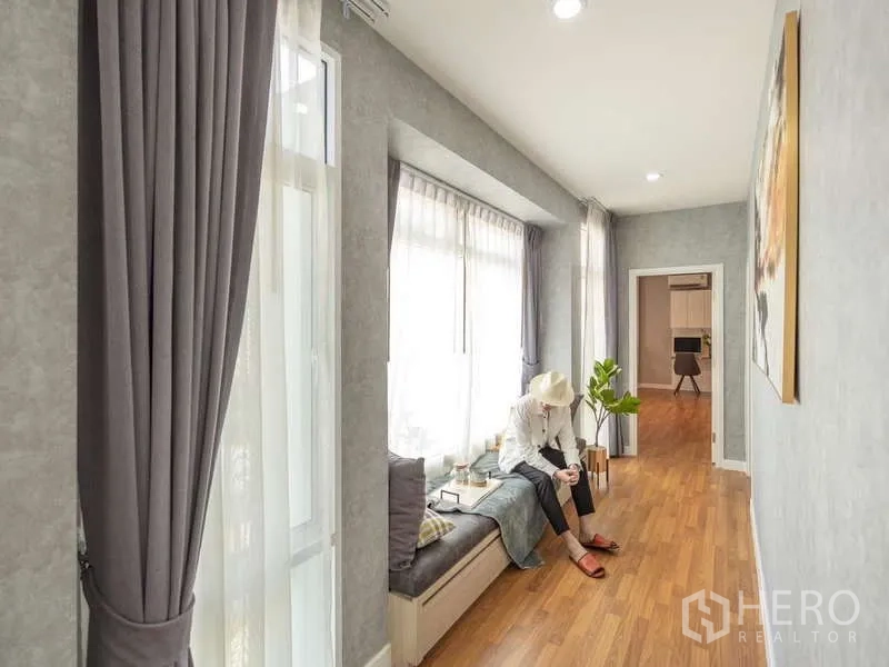 Detached House for sale in Lam Luk Ka, Pathum Thani - Long corridor with window seat and wood flooring leading to rooms.