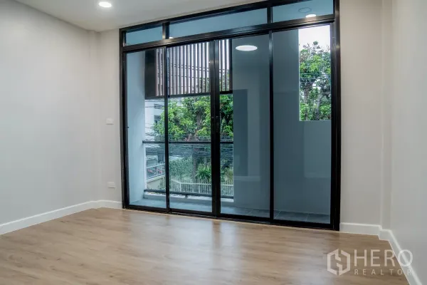 联排别墅 出售在Watthana, Bangkok - 卧室配超大推拉落地门，通阳台，可见绿树景观。