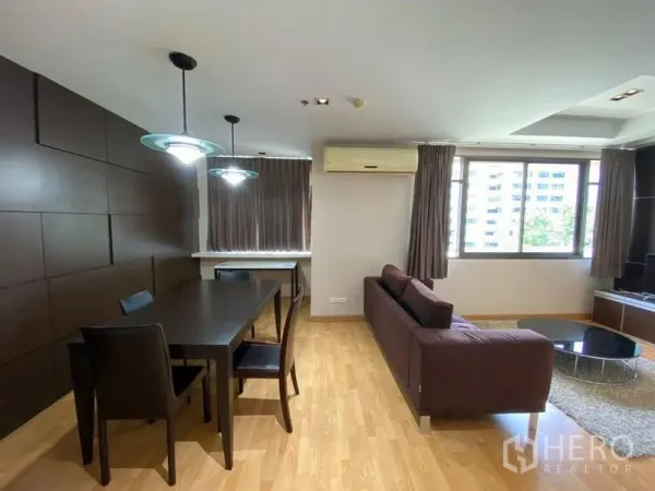 Condominium for rent in Khlong Toei, Bangkok - Dining table and sofa set in a bright open-plan living room with wood flooring.