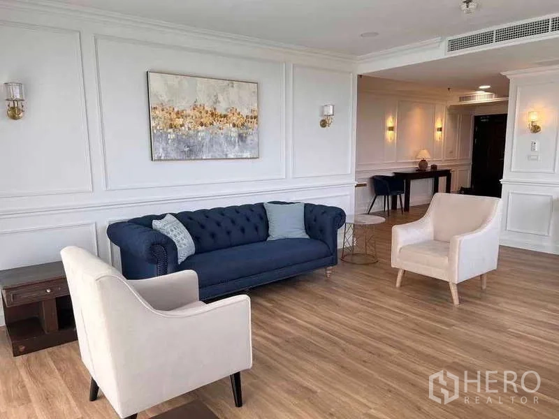 Condominium for rent or sale in Khlong Toei, Bangkok - Bright living room with navy sofa, beige armchairs and warm wood flooring