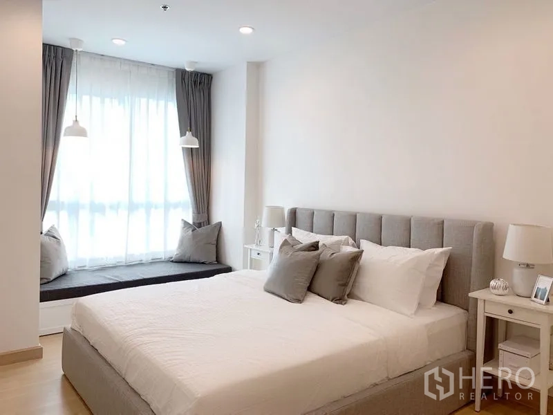 公寓 出售在Yan Nawa, Bangkok - 卧室一角，特大床、床头柜和软垫窗台。