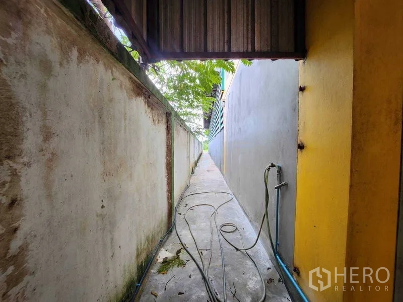 คลังสินค้า ให้เช่าในLat Krabang, Bangkok - ทางเดินแคบข้างอาคารพร้อมสายยางระหว่างกำแพง