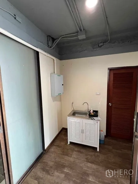 Office Space for rent or sale in Suan Luang, Bangkok - Compact office pantry with sink and storage beside a sliding glass partition.