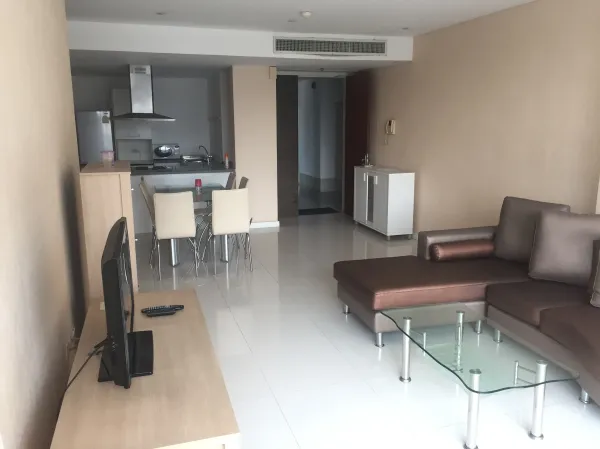 公寓 出租或出售在Watthana, Bangkok - 开放式客餐厅，转角沙发、玻璃茶几、电视柜与现代厨房，位于伊卡迈公寓。