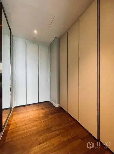 公寓 出租在Pathum Wan, Bangkok - 步入式衣帽间走廊，整面到顶衣柜与温暖木地板。