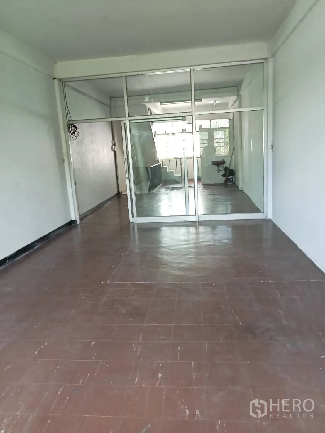Shophouse for rent in Phra Khanong, Bangkok - Upper-floor room with brown tile flooring and a full-height glass partition near the staircase.