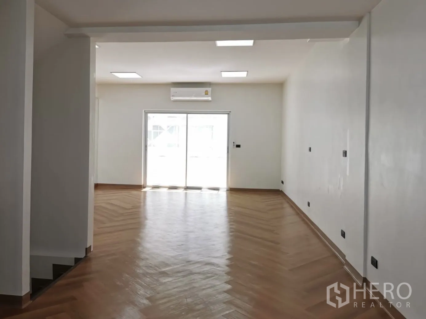 Home Office for rent in Watthana, Bangkok - Deep open-plan office floor with LED panels, herringbone wood flooring and a sliding balcony door.