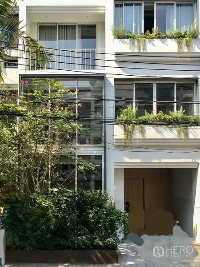 ทาวน์เฮาส์ ให้เช่าในKhlong Toei, Bangkok - หน้าทาวน์เฮาส์สีขาวสามชั้น กระจกบานใหญ่ พร้อมกระบะปลูกต้นไม้เขียวชอุ่ม