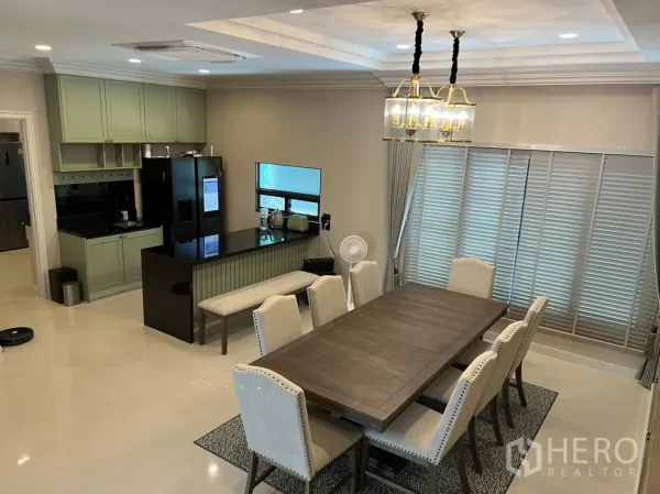 Detached House for rent or sale in Bang Kapi, Bangkok - Open-plan dining area adjoining a stylish island kitchen with black countertops, large windows and soft ceiling lighting.