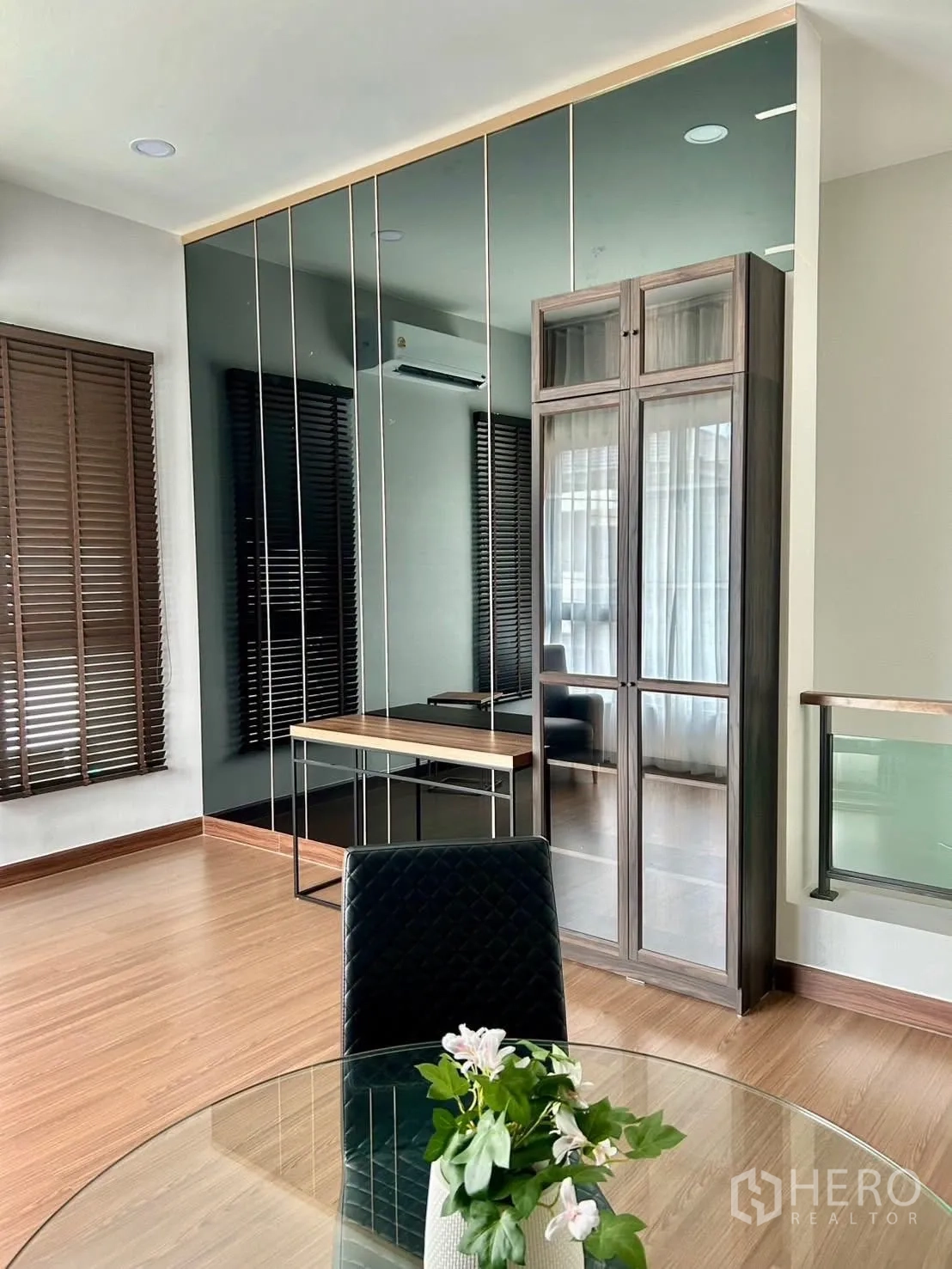 Detached House for rent in Bang Phli, Samut Prakan - Bright corner room with mirror wall panels, a desk, and wood floors.