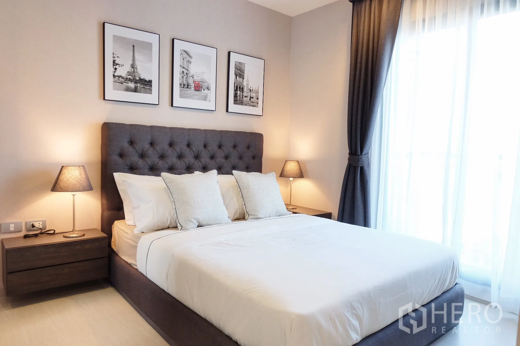 Condominium for rent in Khlong Toei, Bangkok - Cozy bedroom with tufted headboard, bedside lamps and floor-to-ceiling curtains.