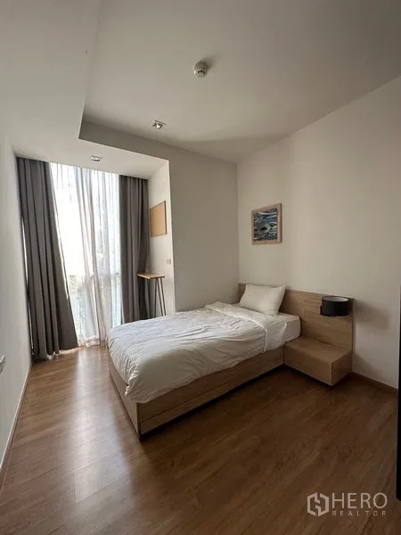 Condominium for rent in Watthana, Bangkok - Second bedroom with single bed, tall window, and wood flooring.