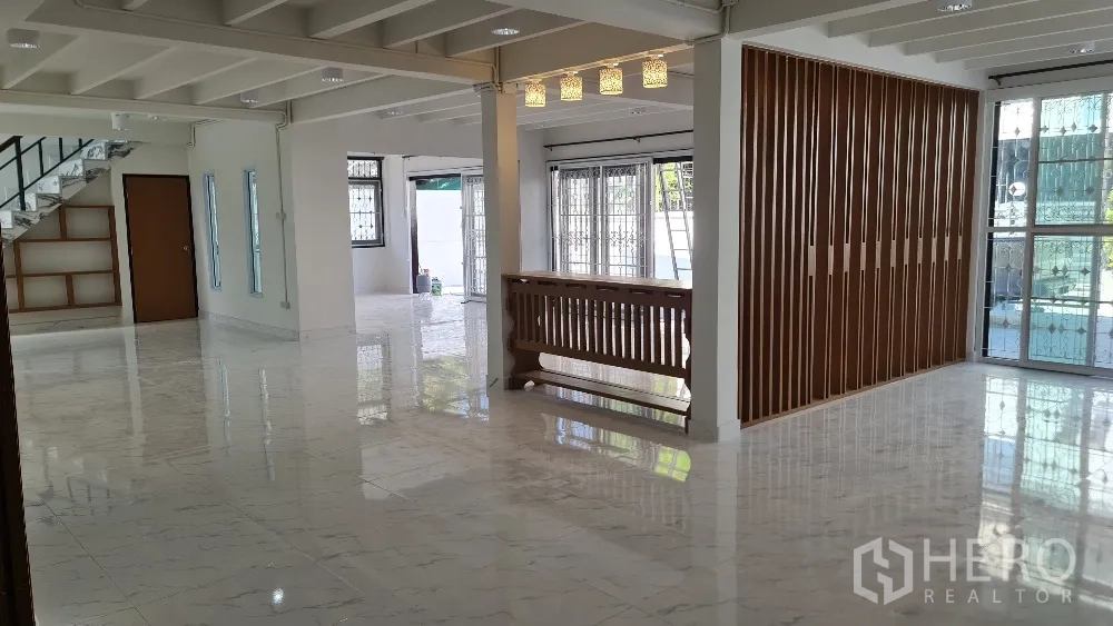 Detached House for rent in Lat Phrao, Bangkok - Bright open-plan living area with glossy marble-look floors and a wood slat divider.