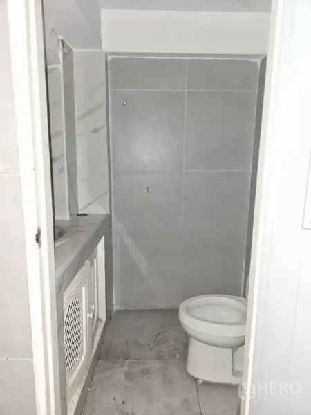Retail Space for rent in Watthana, Bangkok - Compact bathroom with gray wall tiles, toilet and built-in sink counter inside the shop.