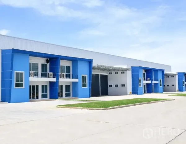 Factory for rent in Bang Sao Thong, Samut Prakan - Modern blue-and-white factory units with front offices, roller shutter doors and a wide driveway inside an industrial compound.
