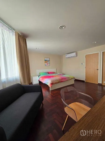 联排别墅 出租在Bang Na, Bangkok - 卧室角度可见空调、沙发与书桌，木质地板。