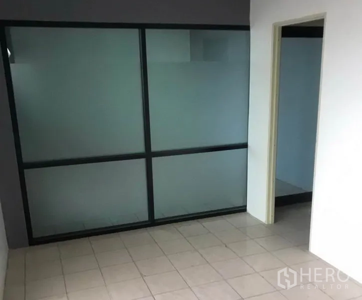 Factory for rent in Bang Bua Thong, Nonthaburi - Compact office area with frosted glass partition and tiled flooring.