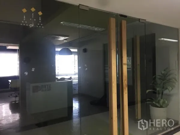 办公空间 出租在Bang Kapi, Bangkok - 玻璃隔断后的接待区，配大窗采光、吊顶照明与室内绿植的现代办公室。