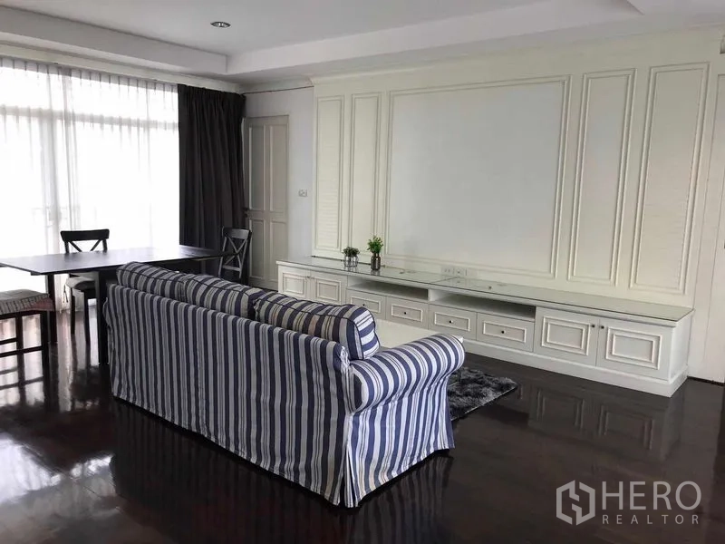 Detached House for sale in Wang Thonglang, Bangkok - Sitting room with striped sofa, dining table and paneled media wall