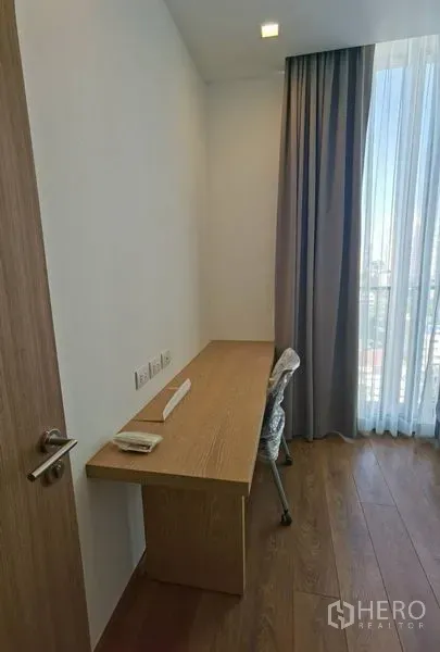 公寓 出租在Watthana, Bangkok - 靠近大窗的内置木质书桌与椅子，城市景观与长窗帘，木地板。