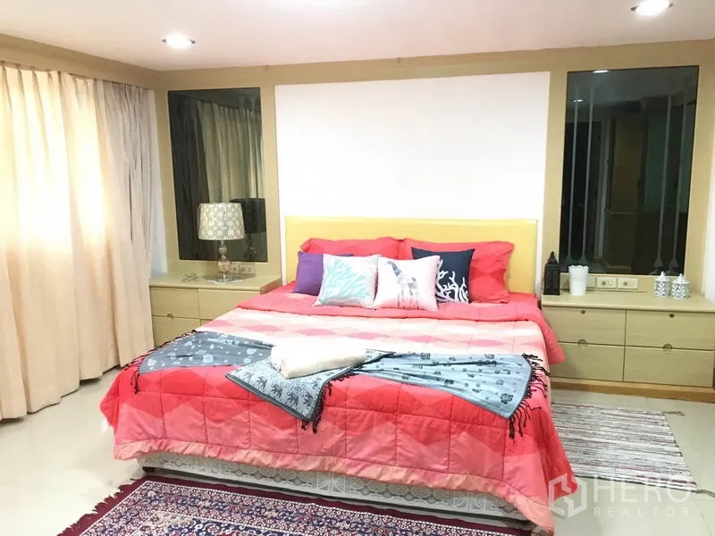 联排别墅 出租在Khlong Toei, Bangkok - 宽敞主卧，特大床红色被褥、床头柜、大窗与地毯。