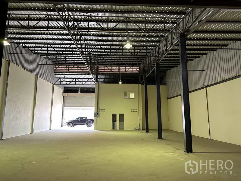 工厂 出售在Mueang Samut Prakan, Samut Prakan - 高挑仓库展示照明、钢梁与大面积可用空间。