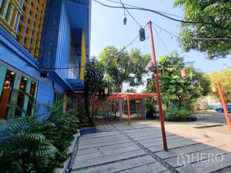 Detached House for rent in Khlong Toei, Bangkok - Courtyard beside the house with string lights, mature trees and wide paved walkway.