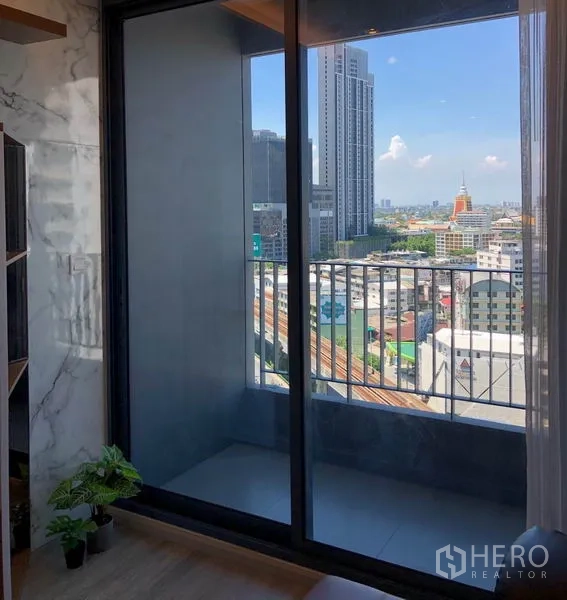 Condominium for rent in Bang Na, Bangkok - Balcony with sliding glass doors overlooking the Bang Na city skyline.