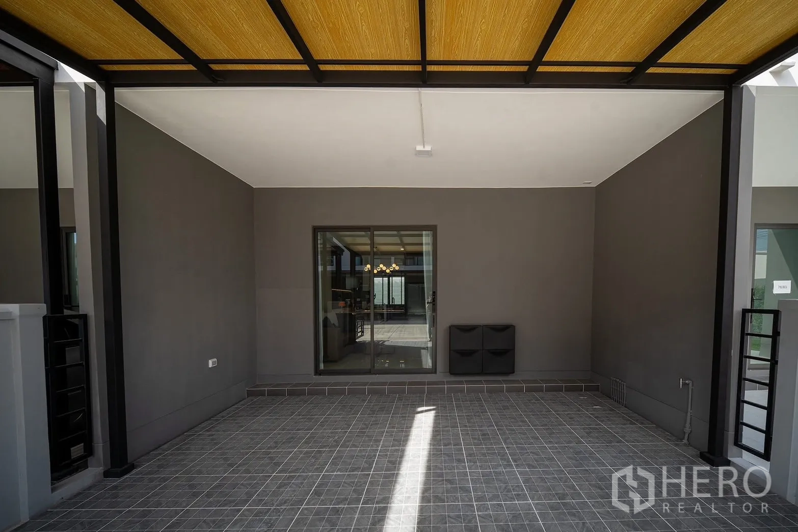 Townhouse for rent in Bang Phli, Samut Prakan - Covered carport with tiled floor and a sliding door into the house.