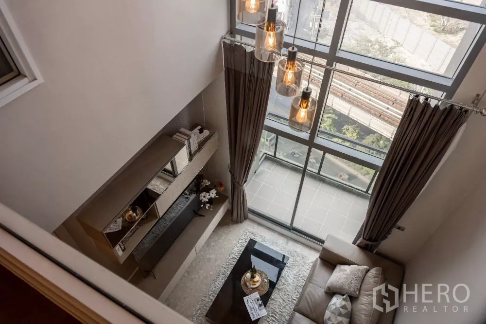Condominium for rent or sale in Khlong Toei, Bangkok - Double-height living room with floor-to-ceiling windows and a compact balcony.